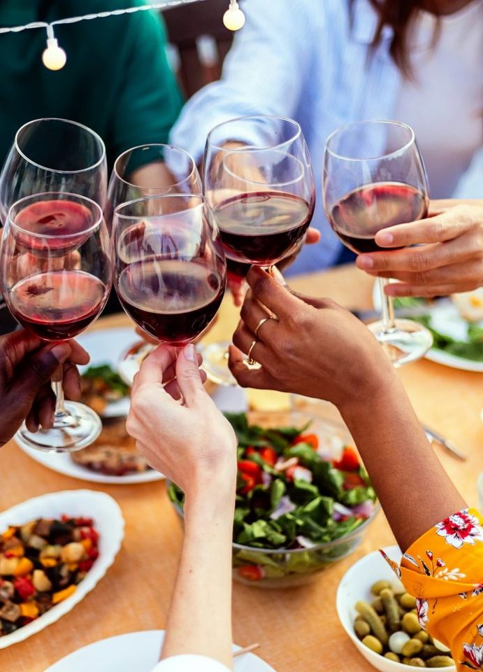 Junger Leute stoßen bei einem gemeinsamen Essen in Biniali auf Mallorca mit Rotwein an