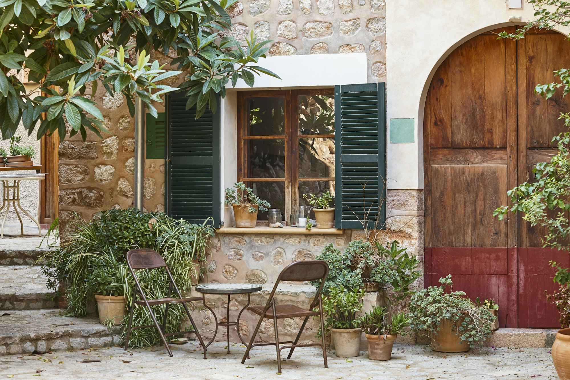 Traditional property with a stone façade decorated with plants in a courtyard in Pollença, Mallorca